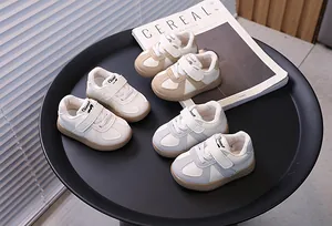 Stylish toddler sneakers in beige, white, and blue displayed on a minimalist black tray.