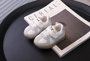 Toddler walking shoes in grey and white with gum soles on a lifestyle background