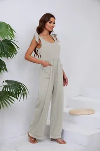 Eleganter hellgrauer Jumpsuit mit weitem Bein, stylischen Schulterschleifen und Taschen.