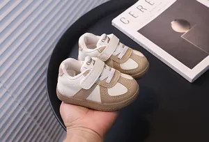 Close-up of toddler walking shoes in beige and white held by hand