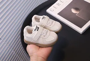 Detailed view of stylish white baby walking sneakers with Velcro straps and gum sole