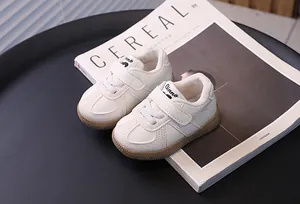 Stylish white toddler sneakers with gum soles and velcro straps on a minimalist background
