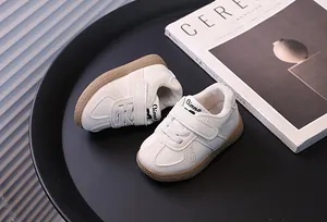 Close-up of minimalist baby white sneakers with brown gum sole and velcro straps