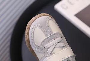 Close-up of children's sneaker toe cap showing stitching and soft leather texture.