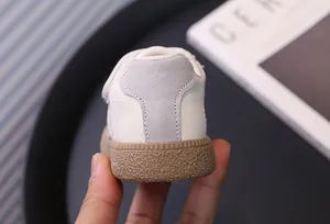 Detailed rear view of white toddler sneakers showing grey heel and tan gum sole