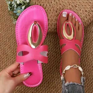 Detail of pink flat thong sandals featuring a decorative gold buckle and summer straw background.