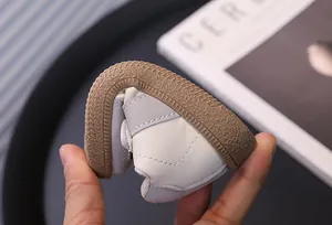 Detail view of flexible sole on white and grey toddler walking sneakers for kids.