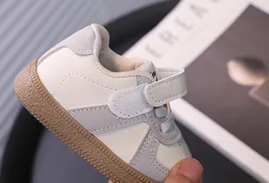 Close-up detail of infant walking shoe with velcro strap and cream grey color design