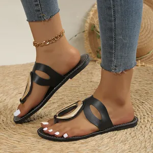 Close-up of stylish black flat sandals for women featuring a large gold metal buckle