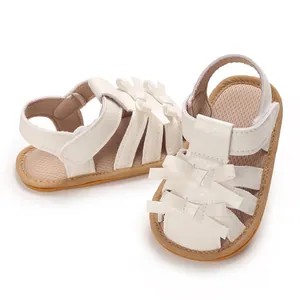 Vista detallada de sandalias blancas para bebé con lazos decorativos y cierre de velcro