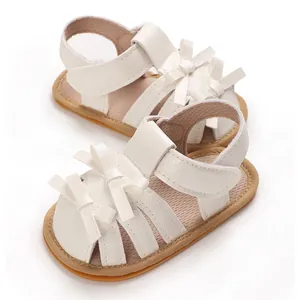 Detalle de sandalias blancas de verano para bebé con suela blanda y lazo decorativo