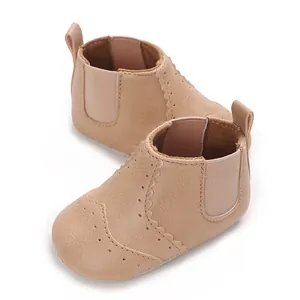 Gedetailleerd beeld van beige baby Chelsea boots met zachte zolen en geperforeerde details