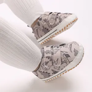 Close-up of baby boy's cartoon dinosaur sneakers with double straps and white rubber toe.