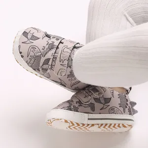 Close-up of baby sneakers with cartoon dinosaur pattern and velcro straps