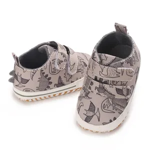 Detailed shot of grey baby shoes featuring a playful black dinosaur cartoon print