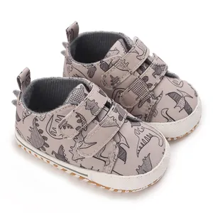 Angled view of baby boy sneakers with cute dinosaur pattern and secure strap closures