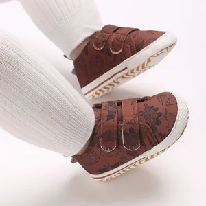 Close-up view of brown baby sneakers with dinosaur prints and double velcro straps