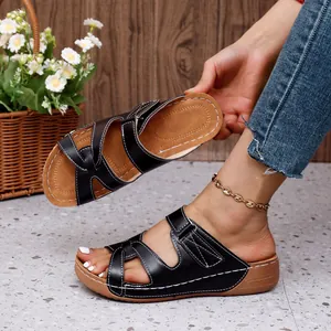 Detalle de sandalias de cuña negras con diseño calado y costuras blancas en contraste.