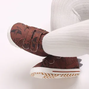 Close-up detail of baby boy brown dinosaur cartoon sneakers with dual Velcro straps