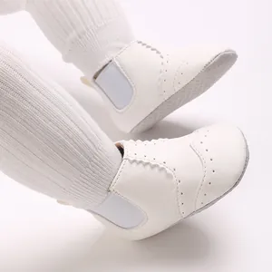 Detailopname van witte, hoge baby loopschoentjes met zachte zool en brogue patroon