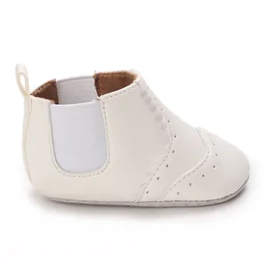 Gedetailleerd overzicht van witte baby-loopschoenen met decoratieve brogue-stiksels