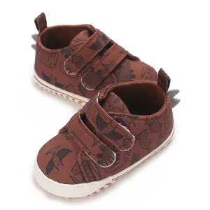 Detailed macro view of brown canvas infant boy sneakers featuring cartoon dinosaur pattern