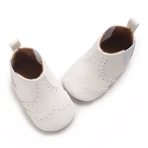 Gedetailleerde weergave van witte zachte baby loopschoentjes met een elegant brogue patroon.