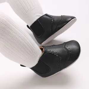Detail van zwarte lederen babyloopschoenen met klassieke brogue-details en zachte zolen