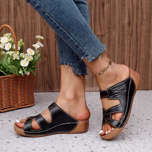 Detalle de sandalias de cuña negras para mujer con diseño calado y costuras blancas