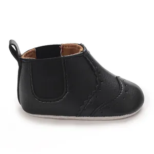 Close-up van zwarte baby Chelsea boots met zachte zool en brogue-patroondetails