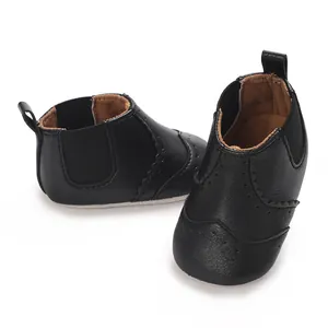 Detailweergave van zwarte baby-loopschoenen van PU-leer met klassieke brogue-details.