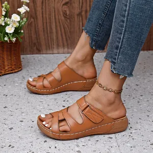 Vista detallada de sandalias de cuña marrones para mujer con tiras caladas y costuras blancas