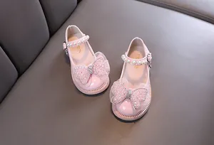 Detail von rosa Mädchen-Prinzessinenschuhen mit glitzernden Schleifen und Perlenriemen.