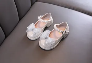 Detailansicht eleganter cremefarbener Mädchen-Spangenschuhe mit Glitzerschleife