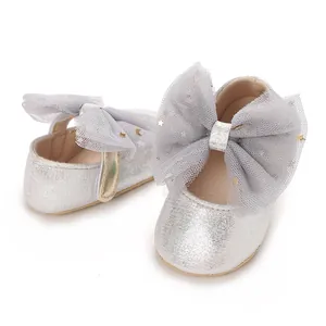Detail van zilveren glitter babyschoentjes met grijze tule strik en sterren.