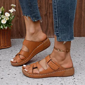 Vista detallada de sandalias con cuña marrones con diseño calado y pespuntes finos