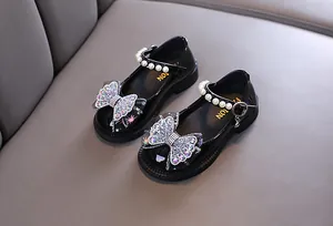 Detailansicht schwarzer Mary Janes mit Strass-Schmetterling und Perlenriemen
