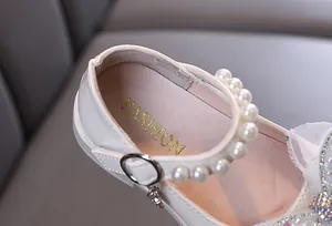 Detailansicht weißer Mädchen-Prinzessinenschuhe mit Perlenriemen und Strass.