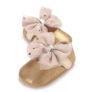 Gedetailleerd macro-overzicht van gouden glitter babyschoentjes met een roze mesh strik