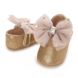 Detail van gouden glitter babyschoentjes met grote roze tule strikken en sterpatroon