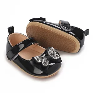Λεπτομερές κοντινό πλάνο μαύρα λουστρίνι παπούτσια μωρού με στρας φιόγκο πεταλούδα