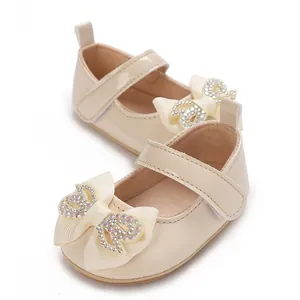Detailed view of beige baby girl walking shoes featuring a rhinestone-embellished bow.