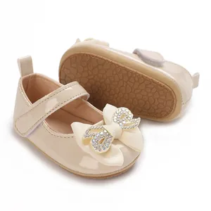 Close-up of beige baby girl walker shoes featuring rhinestone bow and anti-slip sole