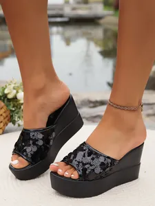 Close-up detail of black sequin platform wedge slippers shown on model outdoors