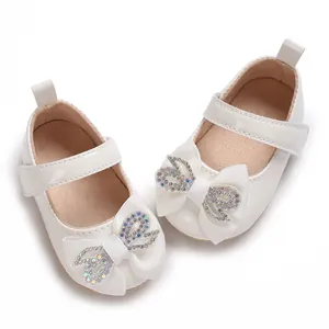 Close-up of white baby girl walker shoes decorated with elegant rhinestone bows