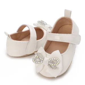 Detail of white baby girl princess shoes with rhinestone bow and soft sole.