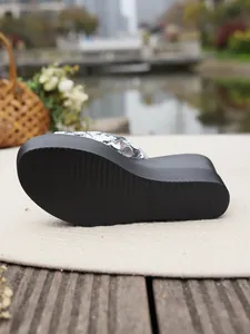 Detailed view of the black non-slip platform outsole on silver sequin wedge slippers