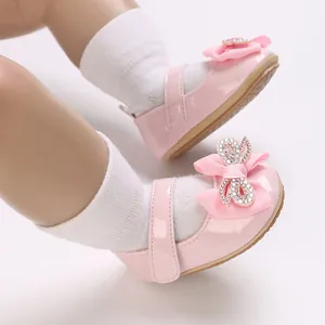 Close-up view of pink baby girl Mary Jane shoes with rhinestone bow and soft sole