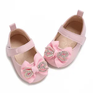 Detailed close-up of pink patent leather baby girl shoes with a rhinestone bow decor