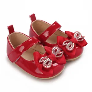 Close-up detail of red baby girl princess shoes featuring a sparkly rhinestone bow design